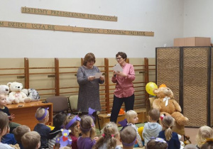 dzieci zebrane na sali słuchają prowadzącej uroczystość nauczycielki